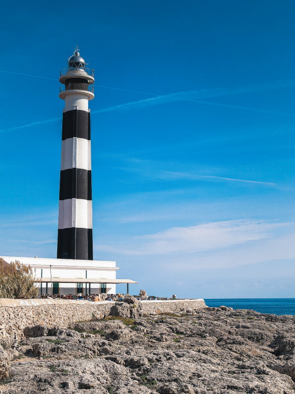 Faro de Cap D'Artutx Menorca Faro de Cap D'Artutx a rayas blanco y azul al lado del mar