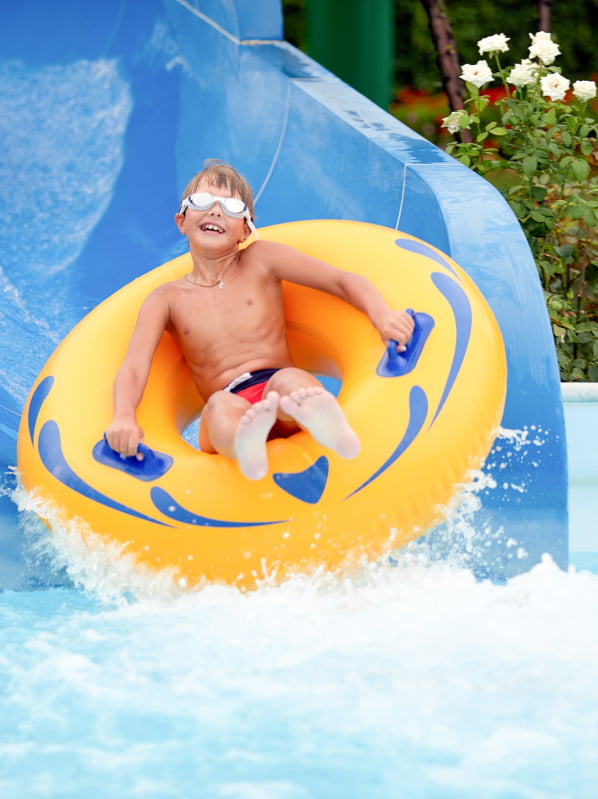 Aquarock park en Cala en Bosc Niño en flotador tirándose por un tobagan de Aquarock Park Cala en Bosc