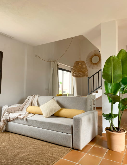 Living room Corner of one of our apartments, with sofa, wicker lamp and plants